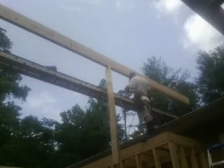 Carpenter setting a ridge beam over a new addition frame — Ice Dam Removal by Roofing Brothers in Leland